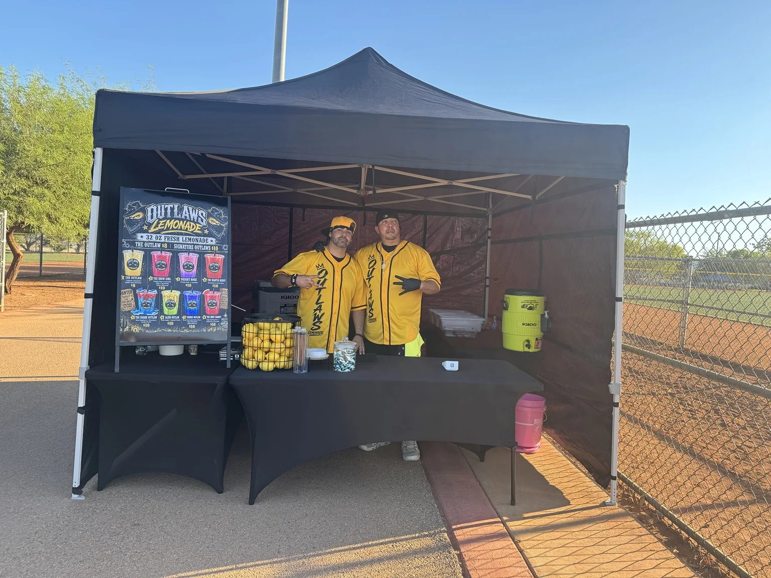The Outlaws Lemonade team in yellow branded jerseys at their black mobile canopy setup